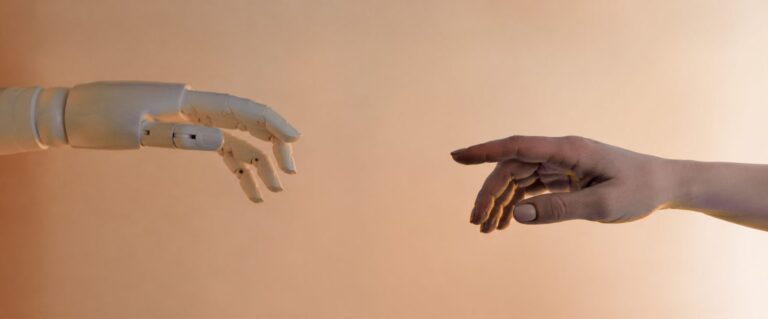 Menschliche Hand und Roboterhand nähern sich einander an – Symbolbild für vertrauensvolle Mensch-KI-Zusammenarbeit